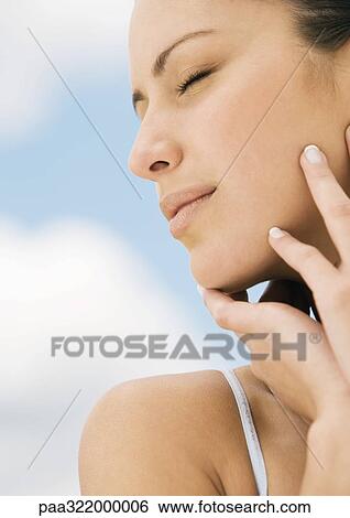 Stock Photograph - Woman with eyes closed touching face. Fotosearch