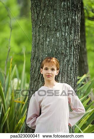 Girl leaning against tree trunk View Large Photo Image Stock Image - Girl leaning against tree trunk. Fotosearch
