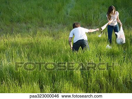 Young couple picking up litter in field View Large Photo Image Stock Photograph - Young couple picking up litter in field. Fotosearch
