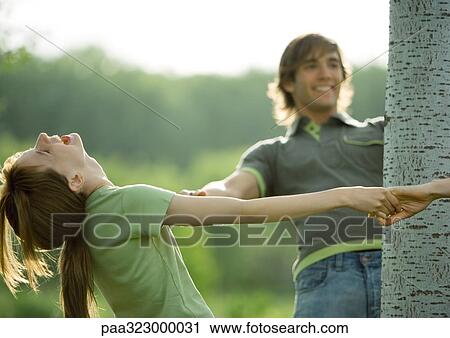 Stock Image - Young people making circle around tree. Fotosearch