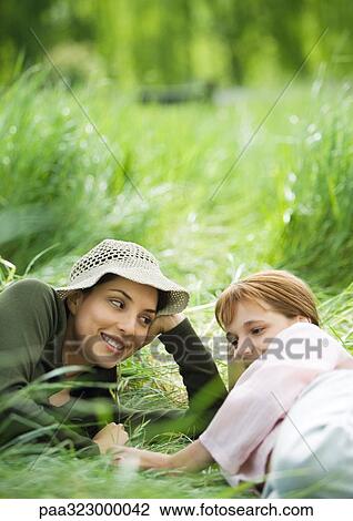 Young woman and girl lying in grass together View Large Photo Image Stock Image - Young woman and girl lying in grass together. Fotosearch