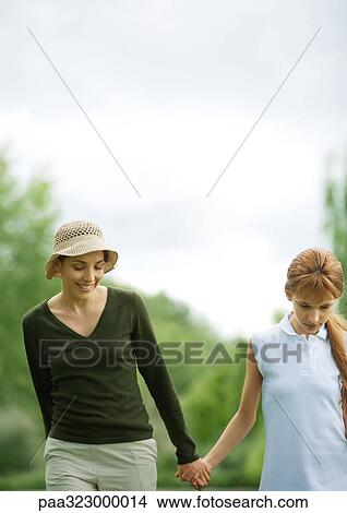 Young woman and girl walking hand in hand View Large Photo Image Picture - Young woman and girl walking hand in hand. Fotosearch