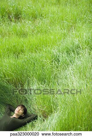 Young woman lying in field View Large Photo Image Stock Image - Young woman lying in field. Fotosearch