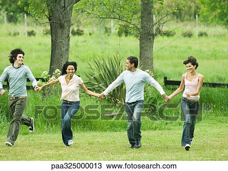 Four young friends holding hands and skipping in field View Large Photo Image Stock Image - Four young friends holding hands and skipping in field. Fotosearch