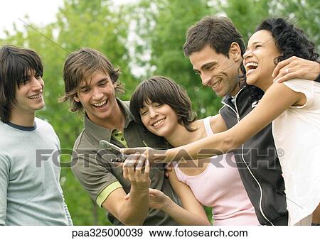 Group of young friends laughing and looking at cell phone View Large Photo Image Stock Photo - Group of young friends laughing and looking at cell phone. Fotosearch