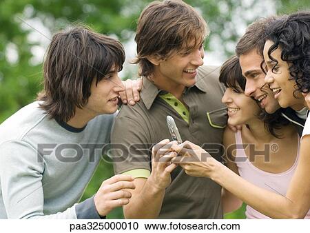 Group of young friends looking at cell phone View Large Photo Image Stock Image - Group of young friends looking at cell phone. Fotosearch
