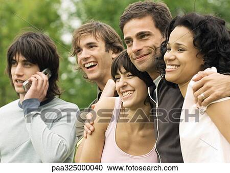 Group of young friends smiling, one using cell phone View Large Photo Image Stock Image - Group of young friends smiling, one using cell phone. Fotosearch