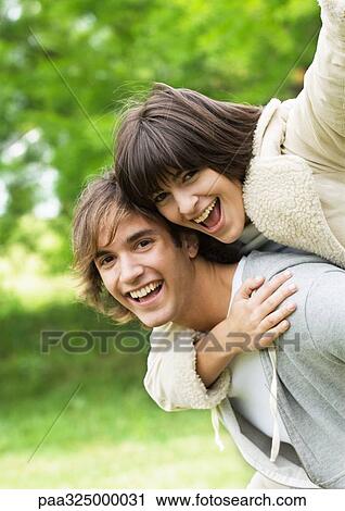 Portrait of smiling young couple, woman on man's back View Large Photo Image Stock Image - Portrait of smiling young couple, woman on man's back. Fotosearch