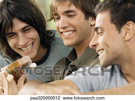Three young male friends, looking at guitar View Large Photo Image Stock Image - Three young male friends, looking at guitar. Fotosearch