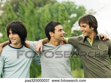 Three young male friends with arms around each other's shoulders View Large Photo Image Stock Photo - Three young male friends with arms around each other's shoulders. Fotosearch