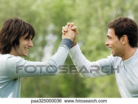 Two young male friends giving each other special handshake View Large Photo Image Stock Photograph - Two young male friends giving each other special handshake. Fotosearch