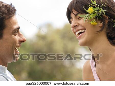 Young couple laughing, woman wearing flowers behind ear View Large Photo Image Stock Photo - Young couple laughing, woman wearing flowers behind ear. Fotosearch