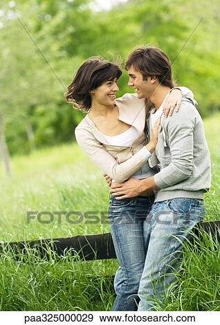 Young couple leaning on a wooden fence, embracing View Large Photo Image Stock Photo - Young couple leaning on a wooden fence, embracing. Fotosearch
