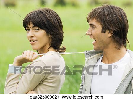 Young couple outdoors, woman pulling string on man's sweatshirt View Large Photo Image Stock Photo - Young couple outdoors, woman pulling string on man's sweatshirt. Fotosearch