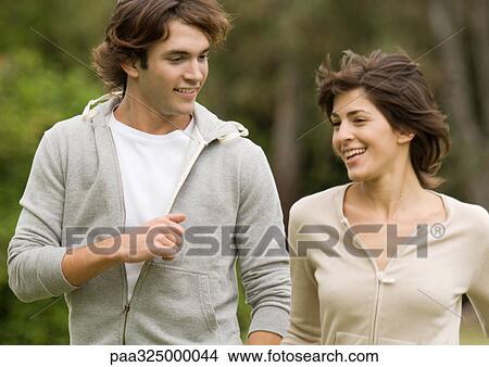 Young couple walking side by side outdoors View Large Photo Image Picture - Young couple walking side by side outdoors. Fotosearch