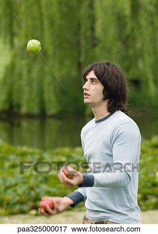 Young man juggling apples outdoors View Large Photo Image Stock Photo - Young man juggling apples outdoors. Fotosearch