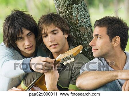 Young man showing friend hand position on guitar View Large Photo Image Stock Image - Young man showing friend hand position on guitar. Fotosearch