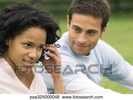 Young woman using cell phone while young man listens View Large Photo Image Stock Photo - Young woman using cell phone while young man listens. Fotosearch