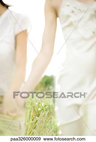 Two young women outdoors, holding hands View Large Photo Image Stock Photo - Two young women outdoors, holding hands. Fotosearch