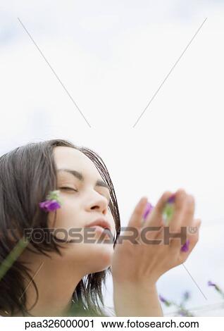 Stock Image - Young woman blowing flowers from hand. Fotosearch
