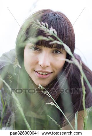 Young woman looking through grass View Large Photo Image Stock Image - Young woman looking through grass. Fotosearch