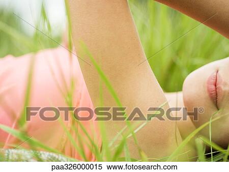 Young woman lying in grass, close-up View Large Photo Image Stock Photography - Young woman lying in grass, close-up. Fotosearch