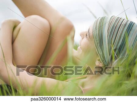 Young woman lying in grass View Large Photo Image Picture - Young woman lying in grass. Fotosearch
