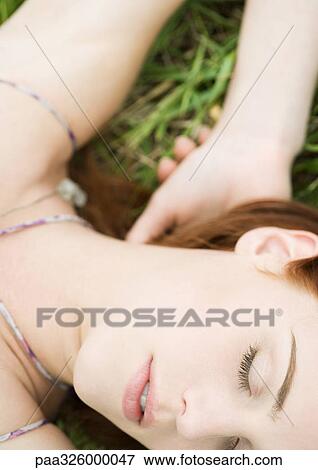 Stock Photo - Young woman lying in grass. Fotosearch