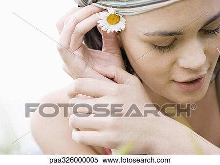 Young woman putting flower behind ear View Large Photo Image Stock Photography - Young woman putting flower behind ear. Fotosearch