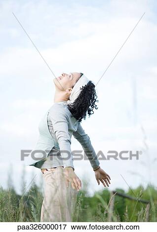 Young woman standing in grass with head and arms thrown back View Large Photo Image Stock Photo - Young woman standing in grass with head and arms thrown back. Fotosearch