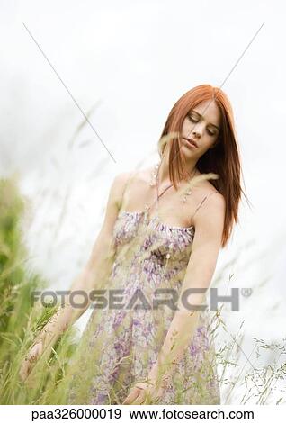 Young woman walking in grass View Large Photo Image Stock Photo - Young woman walking in grass. Fotosearch