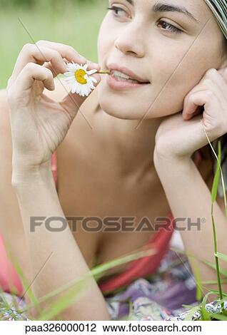 Young woman with flower stem in mouth View Large Photo Image Stock Image - Young woman with flower stem in mouth. Fotosearch