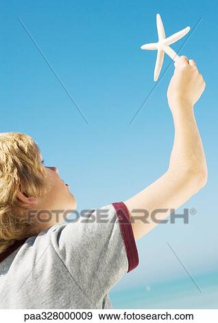 Boy holding up starfish View Large Photo Image Stock Photo - Boy holding up starfish. Fotosearch