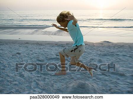 Boy jumping on beach, side view View Large Photo Image Stock Photo - Boy jumping on beach, side view. Fotosearch