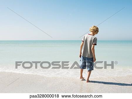 Boy testing water with toe at beach, rear view View Large Photo Image Stock Photo - Boy testing water with toe at beach, rear view. Fotosearch