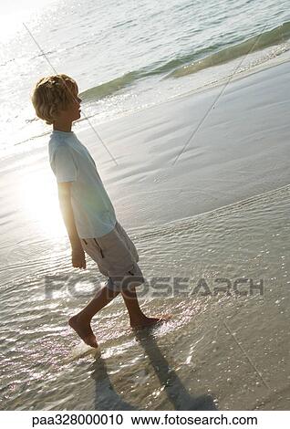 Boy walking in surf at beach View Large Photo Image Stock Image - Boy walking in surf at beach. Fotosearch