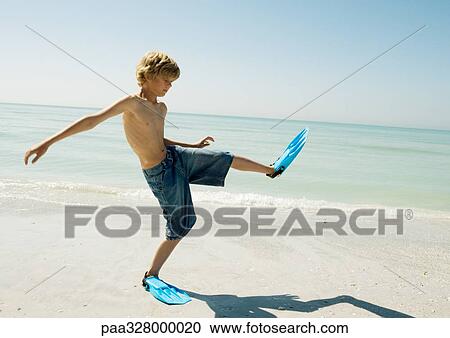 Boy wearing flippers on beach, taking big steps View Large Photo Image Stock Image - Boy wearing flippers on beach, taking big steps. Fotosearch