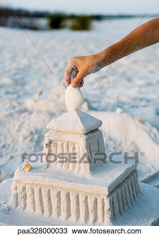 Child placing seashell on top of sand castle View Large Photo Image Stock Image - Child placing seashell on top of sand castle. Fotosearch