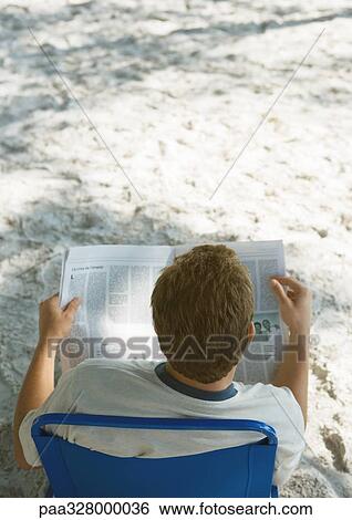 Man sitting in beach chair reading newspaper, rear view View Large Photo Image Stock Photograph - Man sitting in beach chair reading newspaper, rear view. Fotosearch