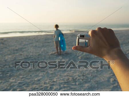 Taking photo of child with digital camera on beach, focus on hand holding camera in foreground View Large Photo Image Stock Image - Taking photo of child with digital camera on beach, focus on hand holding camera in foreground. Fotosearch