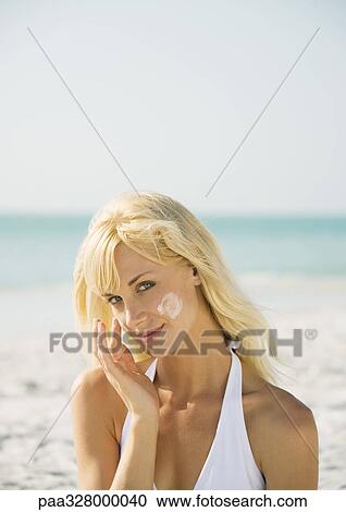 Woman applying sunscreen to face on beach View Large Photo Image Stock Image - Woman applying sunscreen to face on beach. Fotosearch