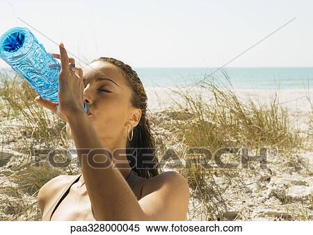 Woman drinking bottled water on beach View Large Photo Image Stock Photography - Woman drinking bottled water on beach. Fotosearch