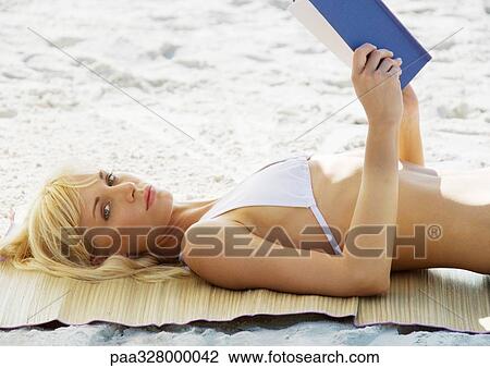 Woman lying on beach with book View Large Photo Image Stock Image - Woman lying on beach with book. Fotosearch