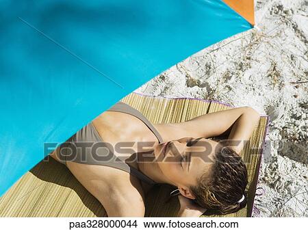 Picture - Woman lying under parasol. Fotosearch