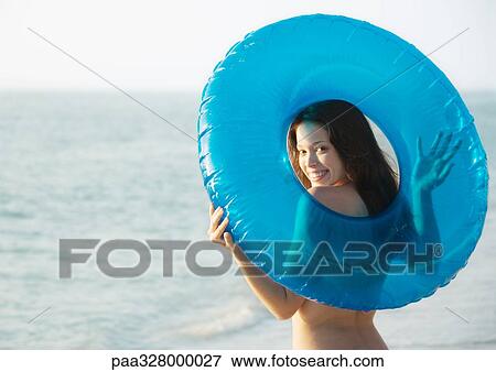 Young woman holding innertube behind back, smiling over shoulder at camera View Large Photo Image Stock Photo - Young woman holding innertube behind back, smiling over shoulder at camera. Fotosearch