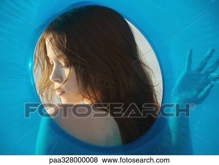 Stock Photo - Young woman's face seen through hole in innertube. Fotosearch