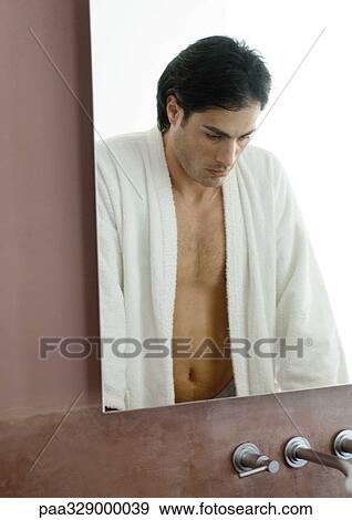 Stock Photo - Man standing in bathroom, looking down. Fotosearch
