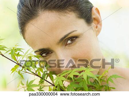 Woman hiding face behind leaves View Large Photo Image Picture - Woman hiding face behind leaves. Fotosearch