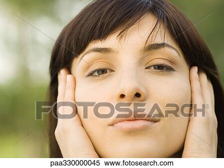 Stock Photography - Woman holding head between hands, close-up. Fotosearch