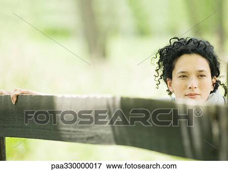 Woman holding onto wooden fence View Large Photo Image Stock Photo - Woman holding onto wooden fence. Fotosearch